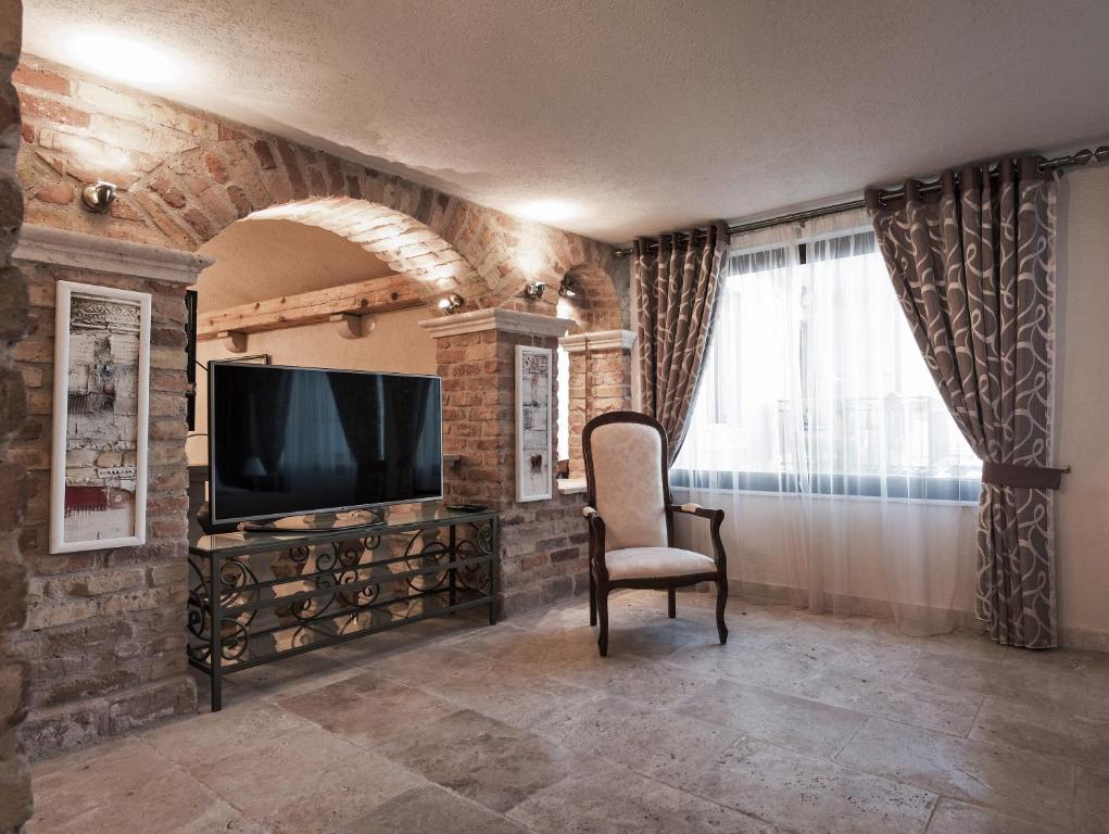 a living room with a television and a chair at Hotel Azimut in Sveti Stefan