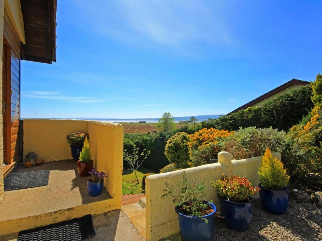 a garden with potted plants on a wall at Achnacarry Cottage in Evelix
