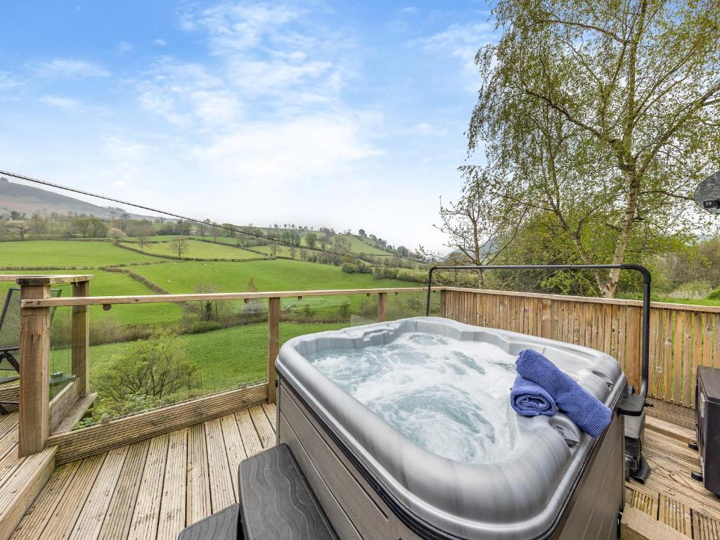 a hot tub on a deck with a view at Wern Ddu Cottage in Pen-y-bont-fawr