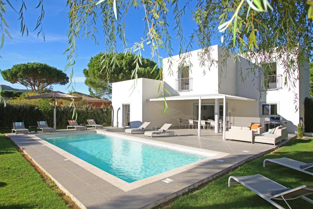 a villa with a swimming pool in front of a house at Domaine Villas Mandarine Private Pools & Spa in Calvi
