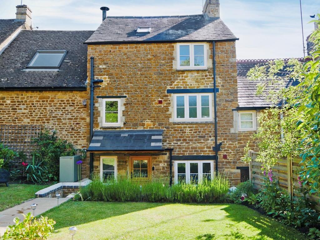 an exterior view of a brick house with a garden at Wells Cottage in Hook Norton
