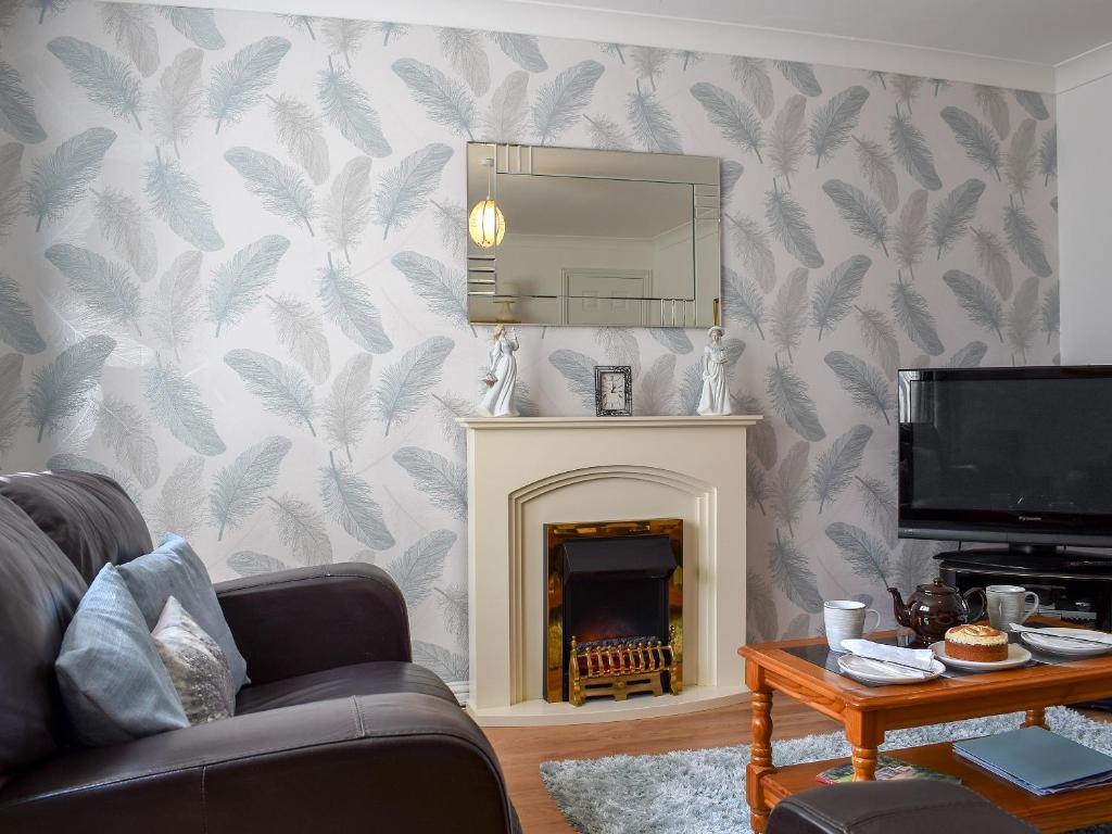 a living room with a fireplace and a mirror at The Marches in Anstruther