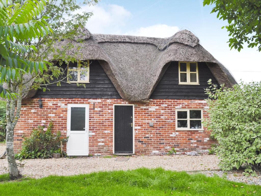 a thatch roofed house with a white door at Walnut Tree Cottage in Burbage