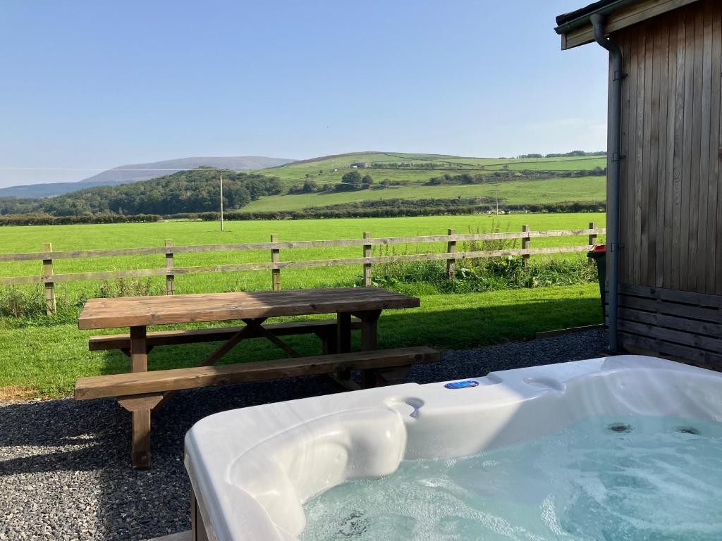 a hot tub with a picnic table and a bench at Willow Lodge - Uk13637 in Creetown