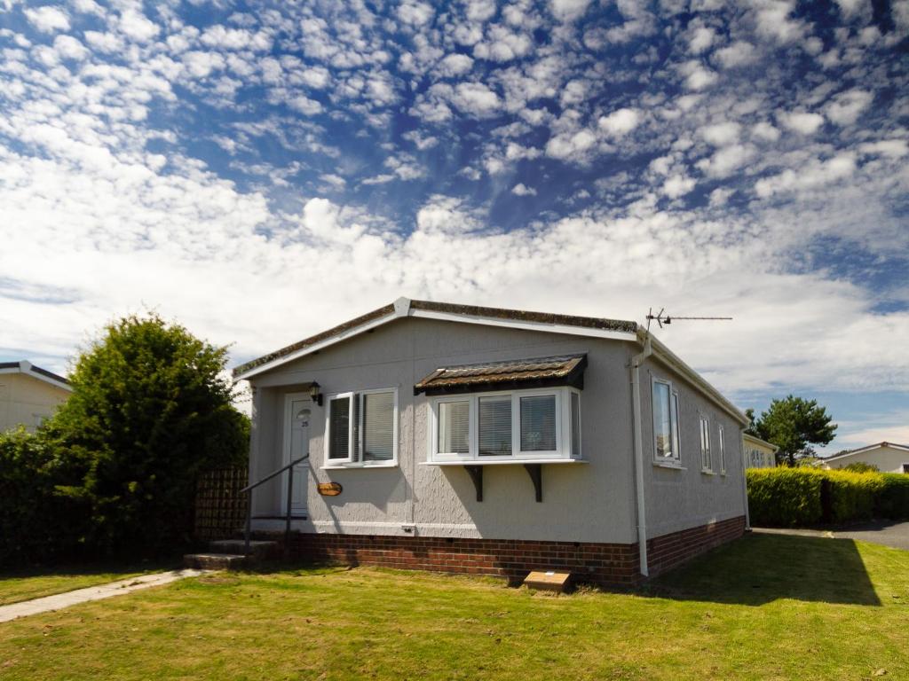 a small house in a yard with a cloudy sky at Lazy Daize in Saint Merryn