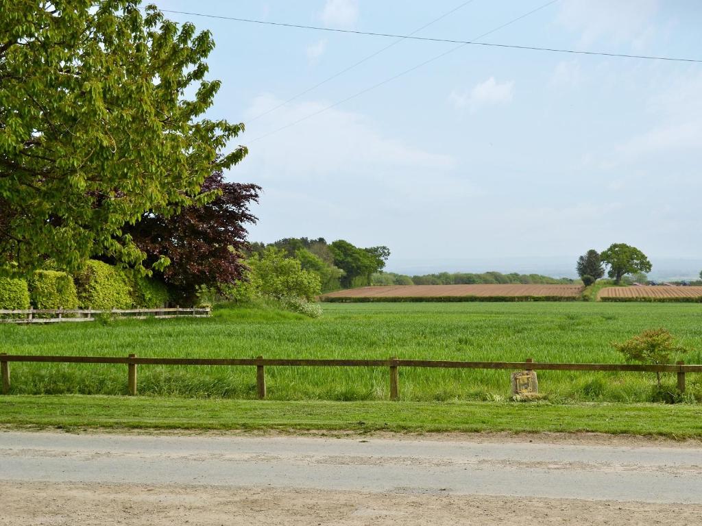 a field of green grass next to a wooden fence at Elm Tree Cottage in Kirkbymoorside