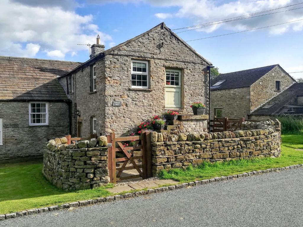 a stone house with a stone retaining wall at Timbessie Barn in Carperby