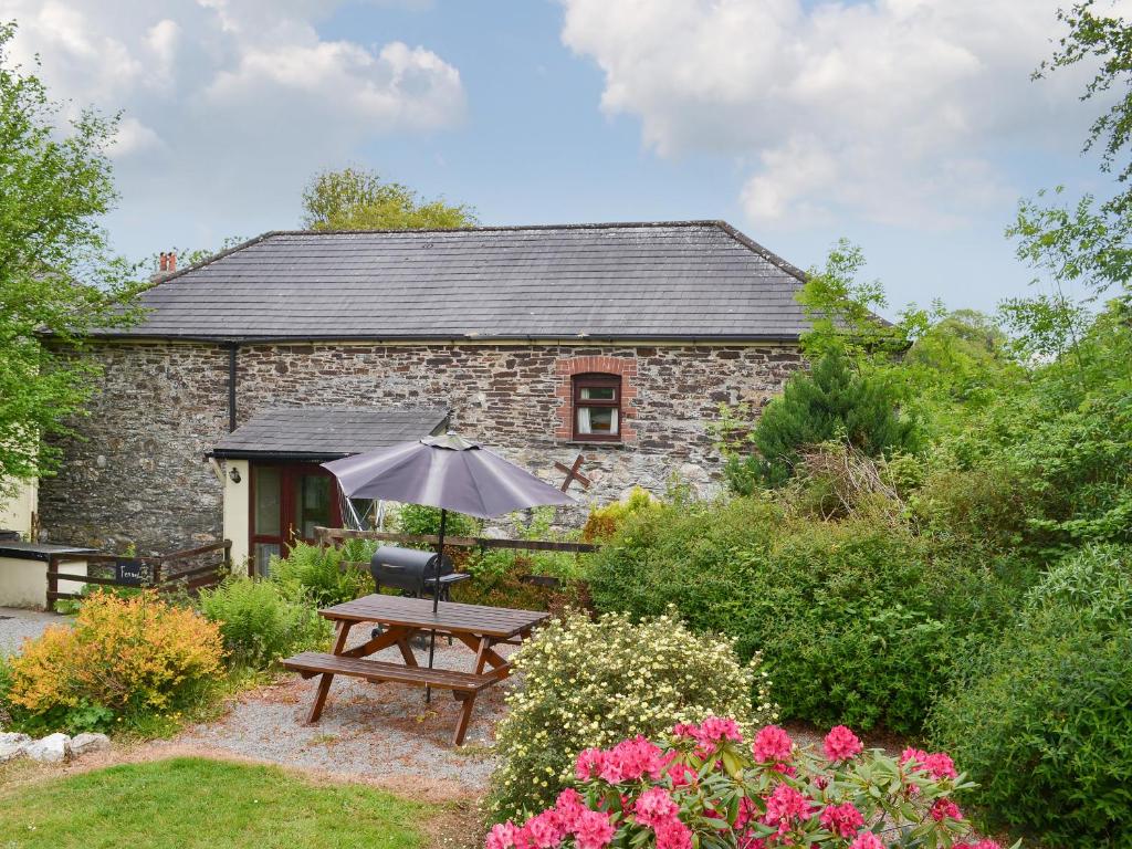 a stone cottage with a picnic table and an umbrella at Fennel in Kelly