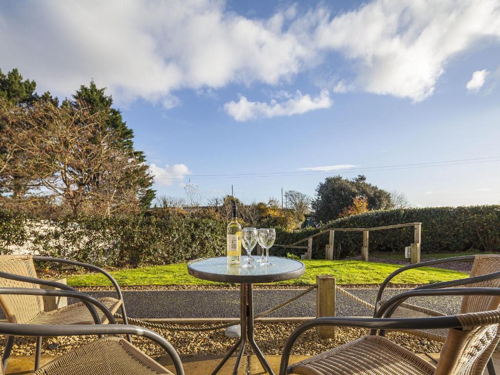 a table with wine glasses and chairs on a patio at 5 Red Rock Apartments in Dawlish Warren