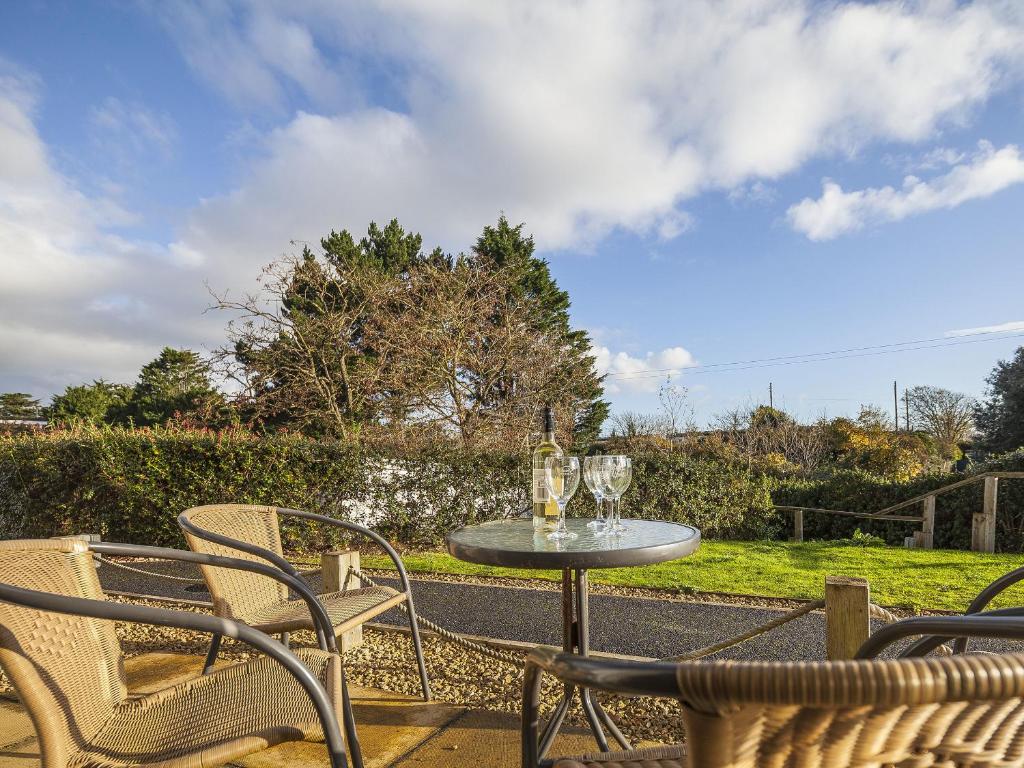 a table with wine glasses and chairs on a patio at 4 Red Rock Apartments in Dawlish Warren