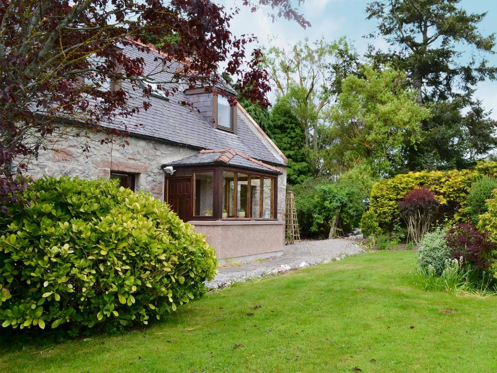 an old stone house with a window and a yard at Old Post Office House in Knockbain