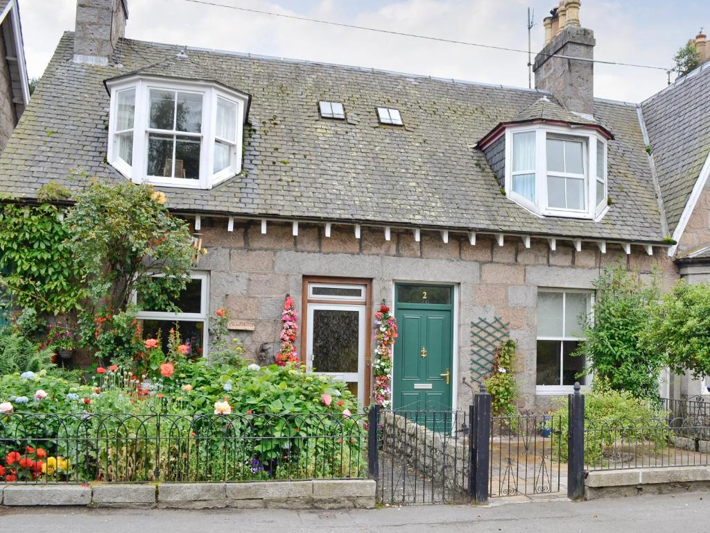 a house with a green door and a fence at Viewington Lodge in Ballater