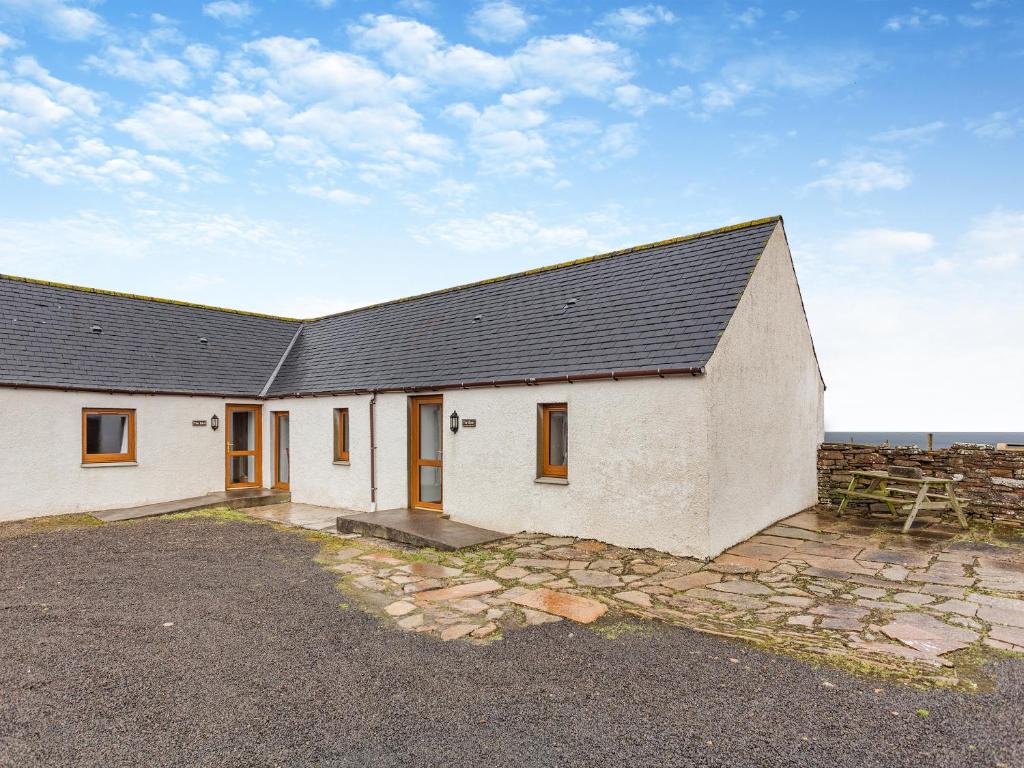a large white building with a black roof at The Byre Mey in Scarfskerry