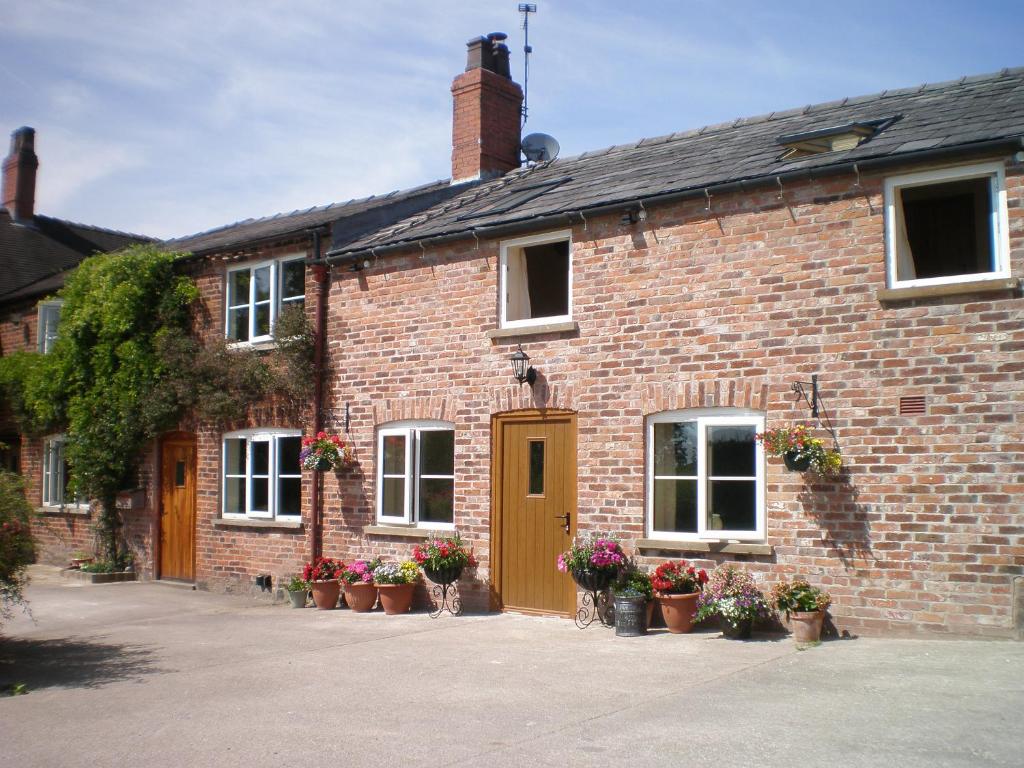 a brick house with potted plants in front of it at Farmhouse Cottage in North Rode