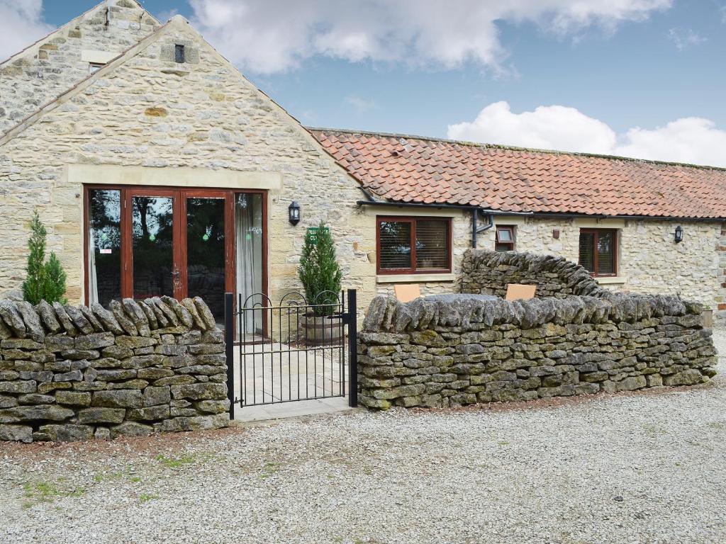 a stone house with a gate and a stone wall at Plum Tree Cottage in Kirkbymoorside