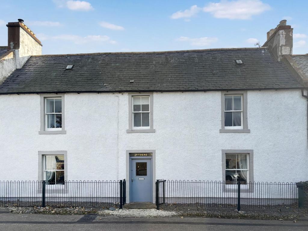 a white house with a fence in front of it at Ivydene Cottage in Cromarty