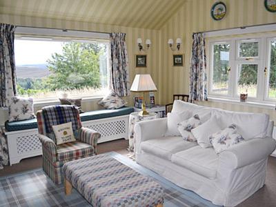 a living room with a white couch and a chair at Reid's Cottage in Lairg