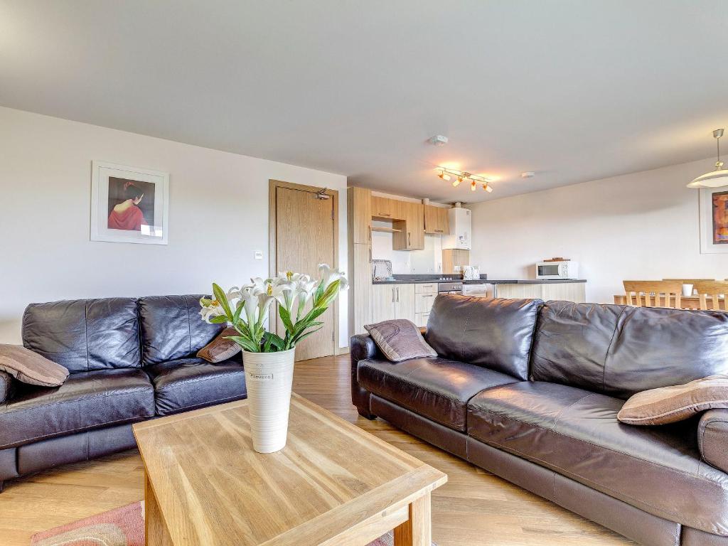 a living room with a leather couch and a table at 14 Red Rock Apartments in Dawlish Warren