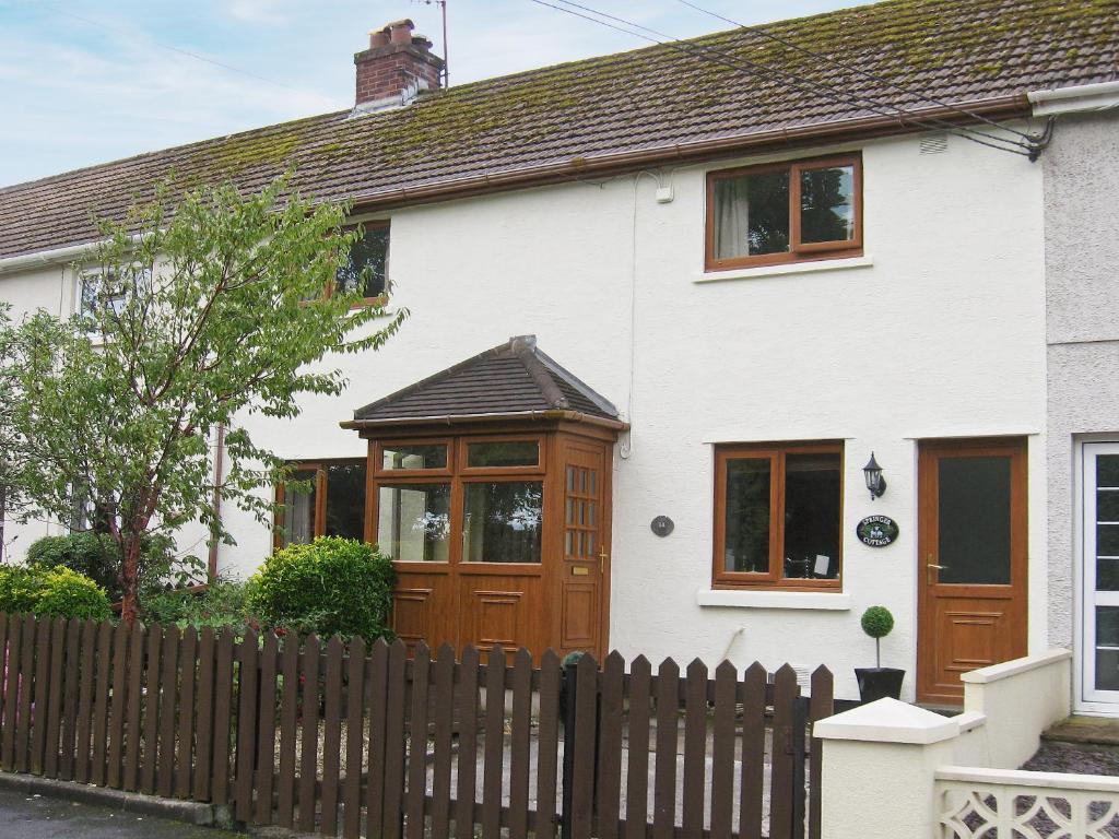 a white house with a wooden door and a fence at Springer Cottage in Llanstephan