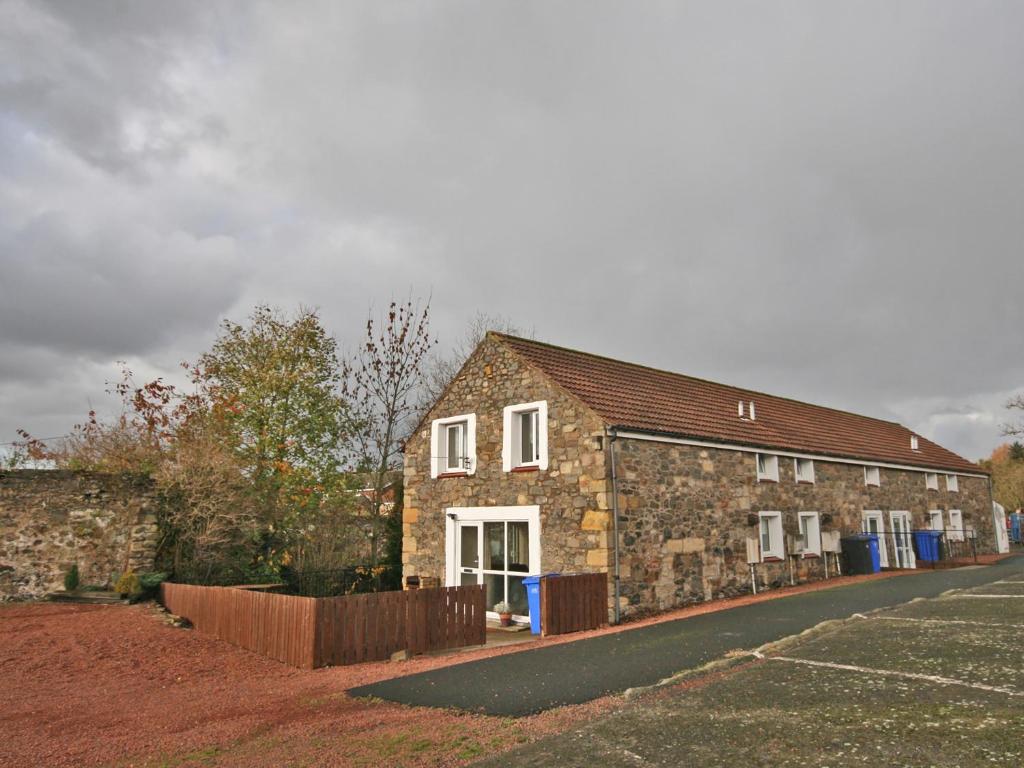 a stone building with a fence in front of it at St Abbs Cottage in Belford