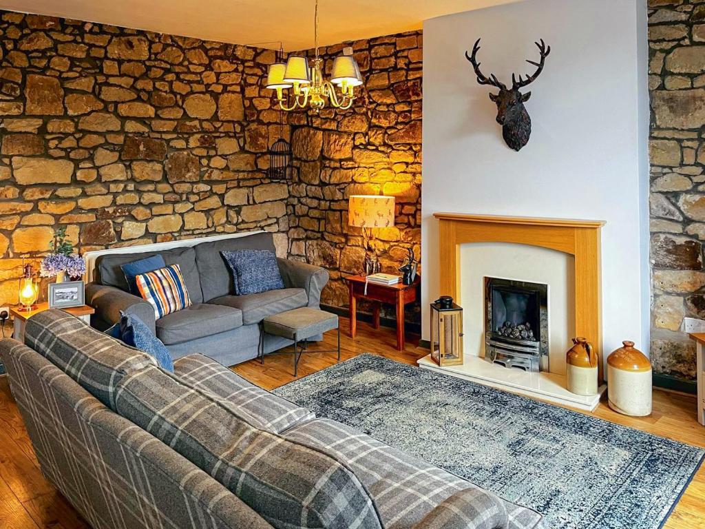 a living room with a couch and a fireplace at Bertram Cottage in Swarland