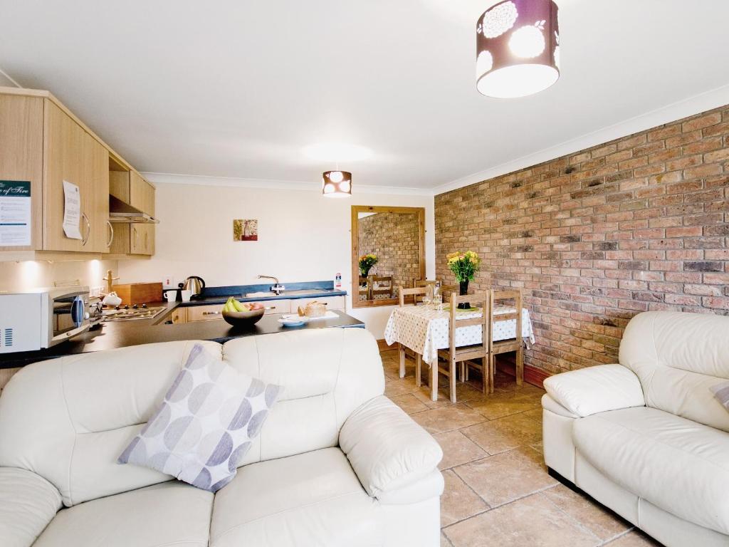 a living room with two white couches and a brick wall at Close Cottage - W41944 in Filey