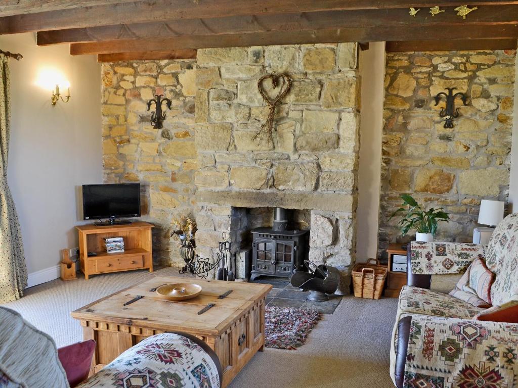 a living room with a stone wall with a fireplace at Sandsedge Cottage in Ellington
