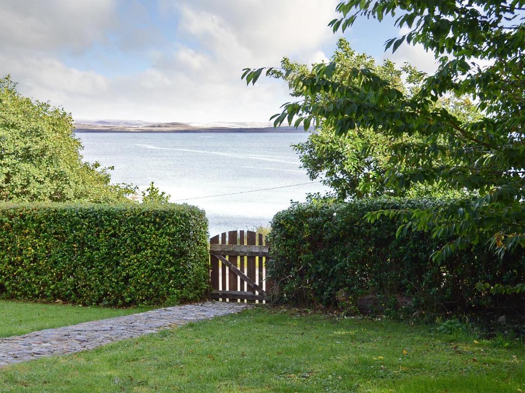a wooden fence in front of the water at Deo Na Mara in Midtown Brae