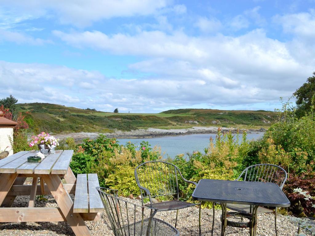 a picnic table and chairs next to a river at Port Righ Cottage in Carradale