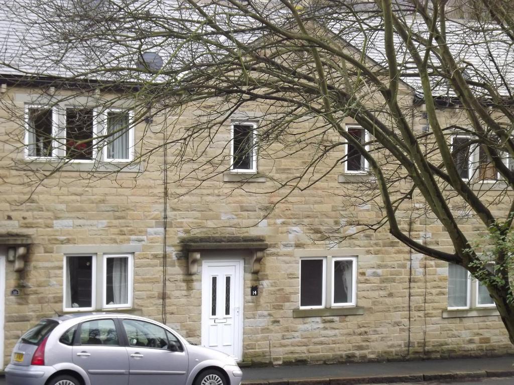 a stone house with a car parked in front of it at Belle Isle Cottage in Haworth