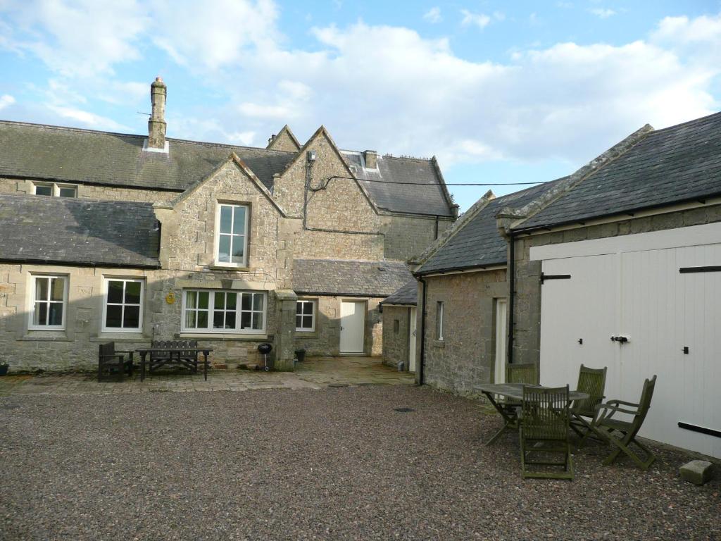 an old stone house with a white garage at Granary Cottage Whittingham in Whittingham