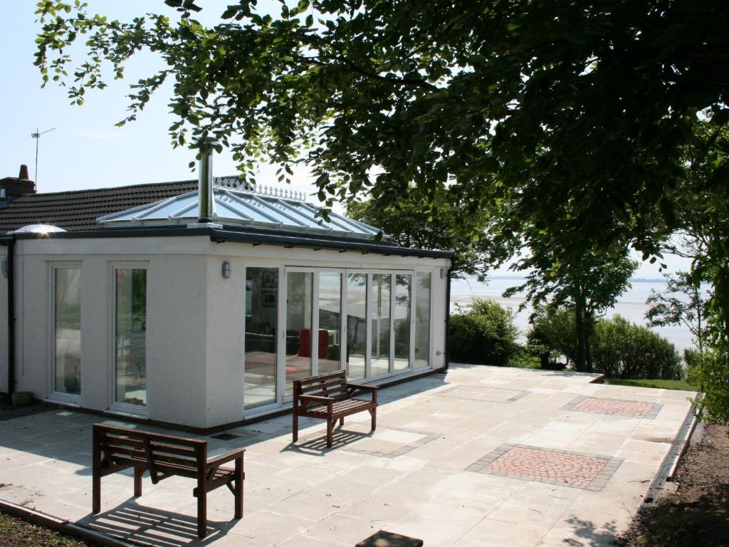 a conservatory with two benches on a patio at Dornock Brow Cottage in Dornock