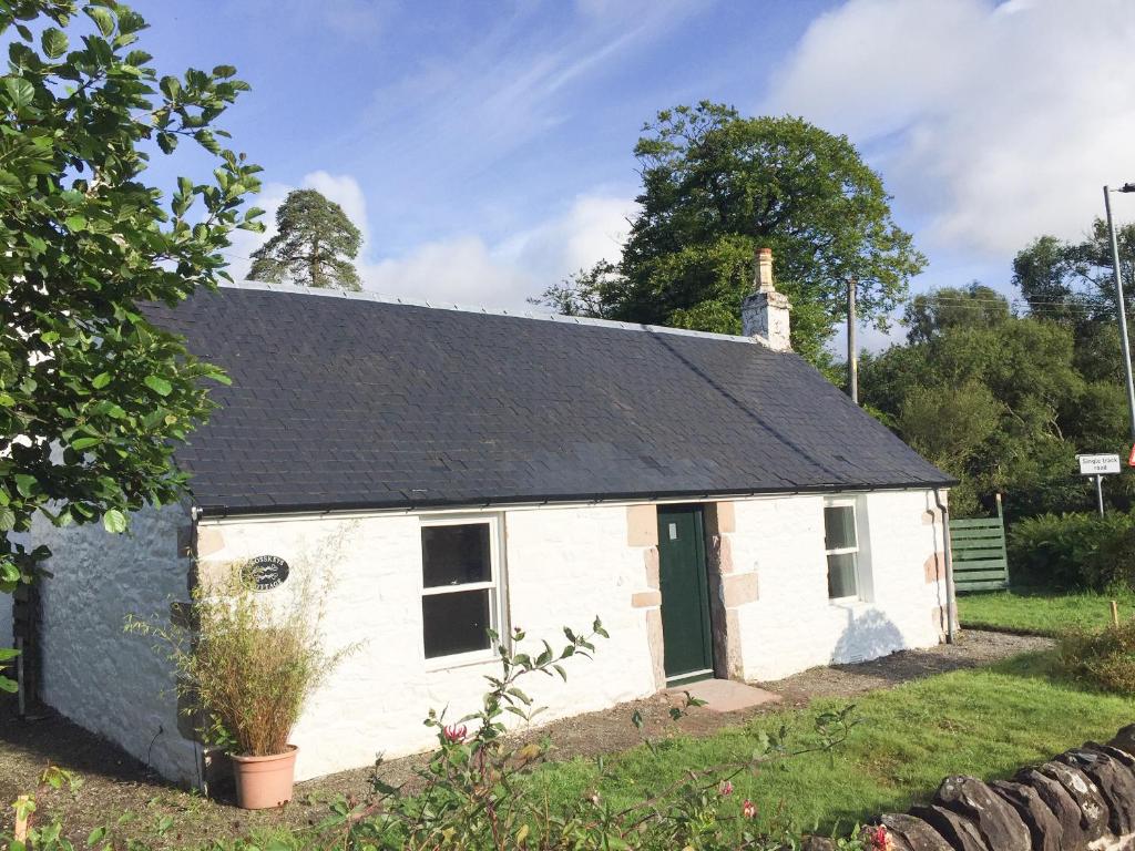 a white cottage with a black roof at Crosskeys Cottage in Shandon