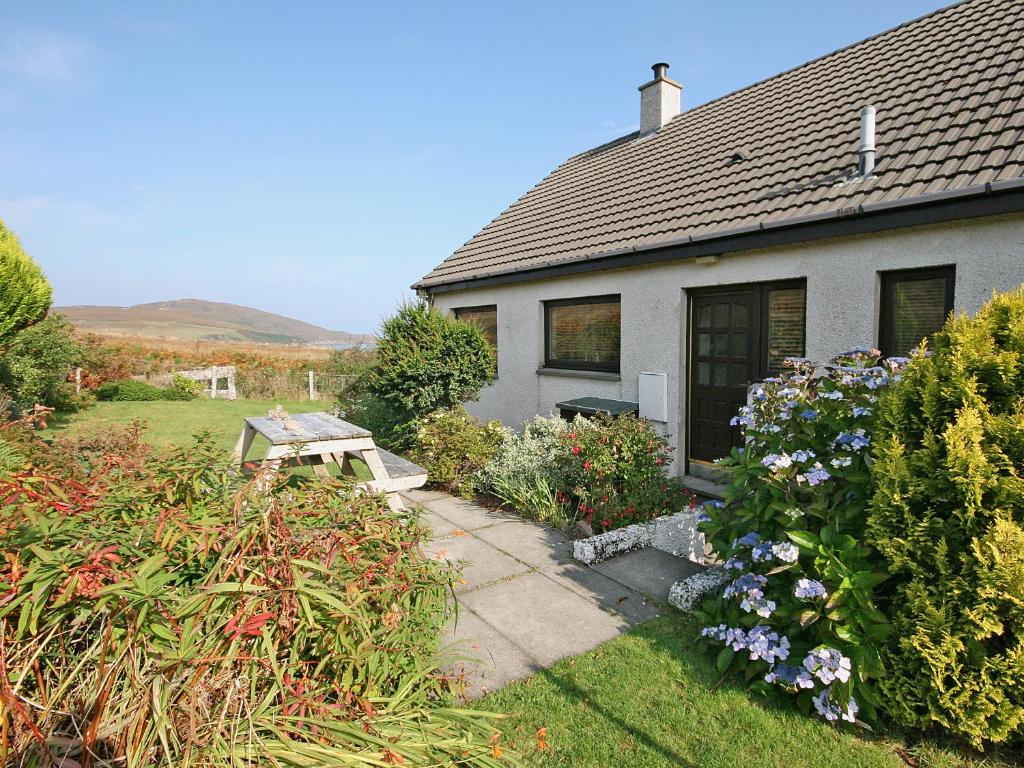 a house with a bench and flowers in front of it at Kildonan in Laide
