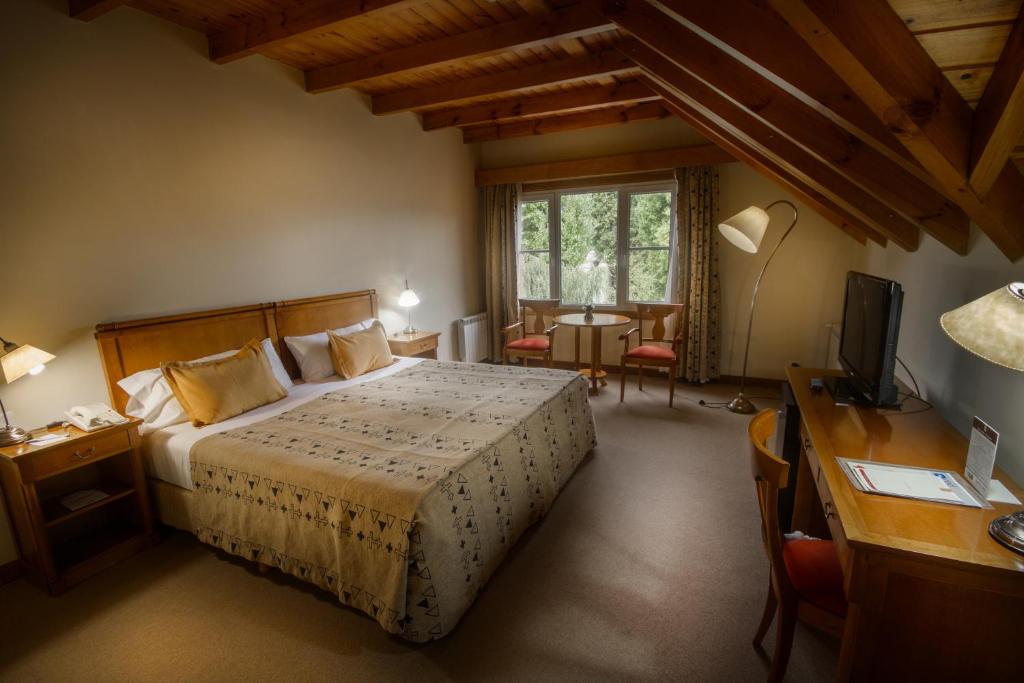 Schlafzimmer mit einem Bett, einem Schreibtisch und einem TV in der Unterkunft Hotel Kosten Aike in El Calafate