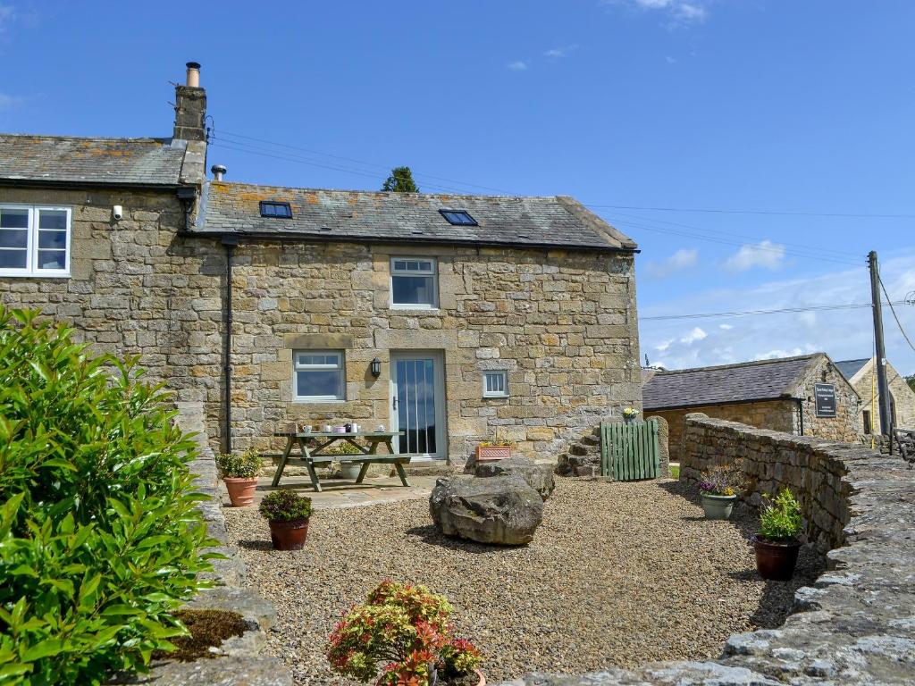 a stone house with a picnic table in front of it at Knoppingsholme Stable in Greenhaugh