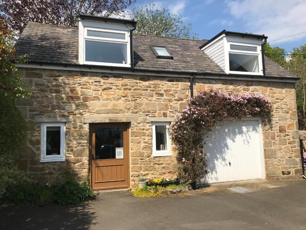 a stone house with a white door and windows at The Smithy in Ovingham