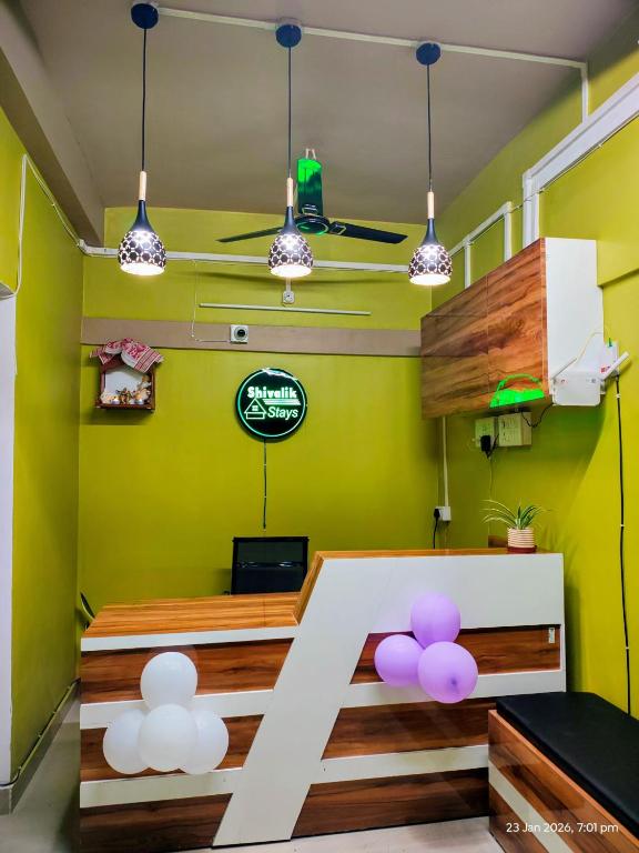 a room with green walls and a table with purple balloons at Shivalik stays in Jorhat
