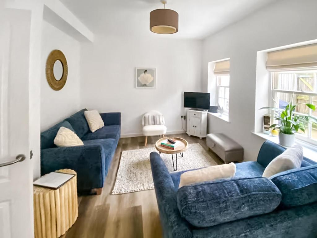 a living room with blue couches and a tv at Surf Cottage in Cromer
