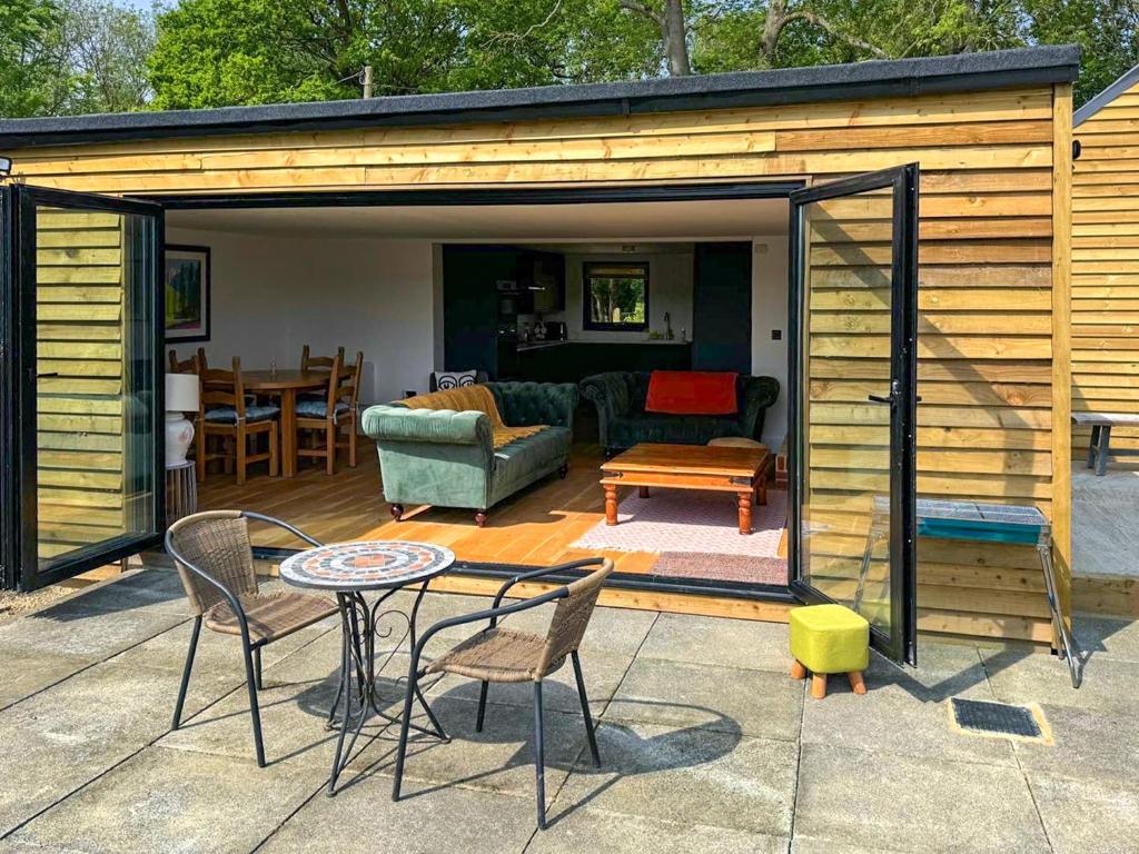 a patio with a table and chairs and a shed at Fernhill Stables in Sevenoaks