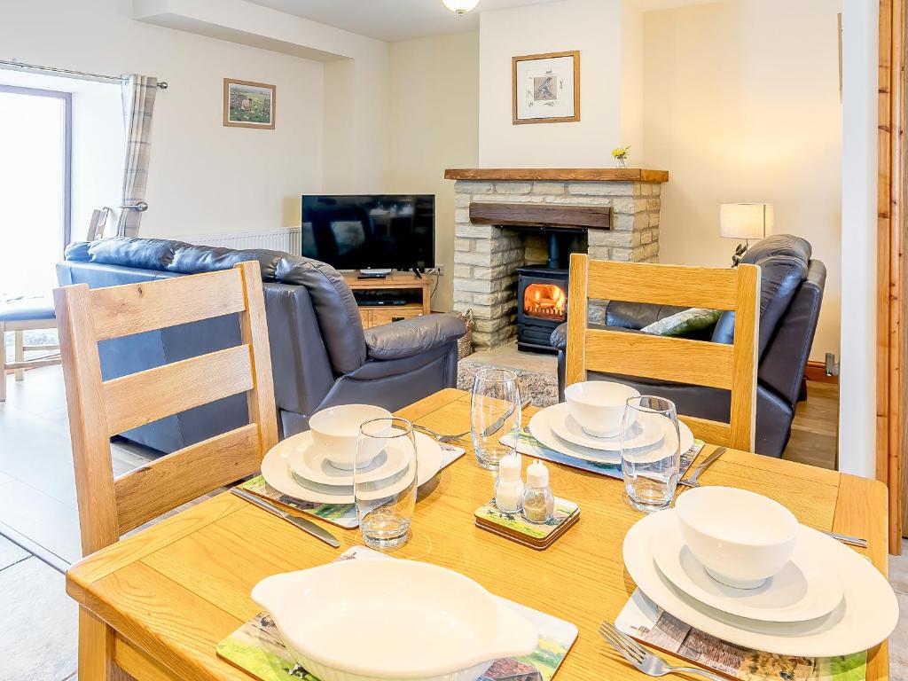 a dining room with a table with chairs and a fireplace at Shepherd's Nook - Uk32388 in Dunford Bridge