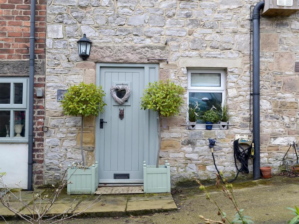 a stone house with a blue door and two windows at The Old Cobblers Cottage in Bakewell