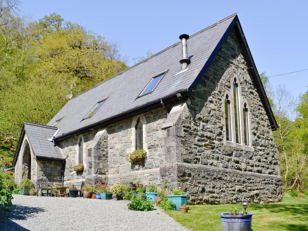 an old stone church with plants in front of it at St John The Baptist in Capel Curig