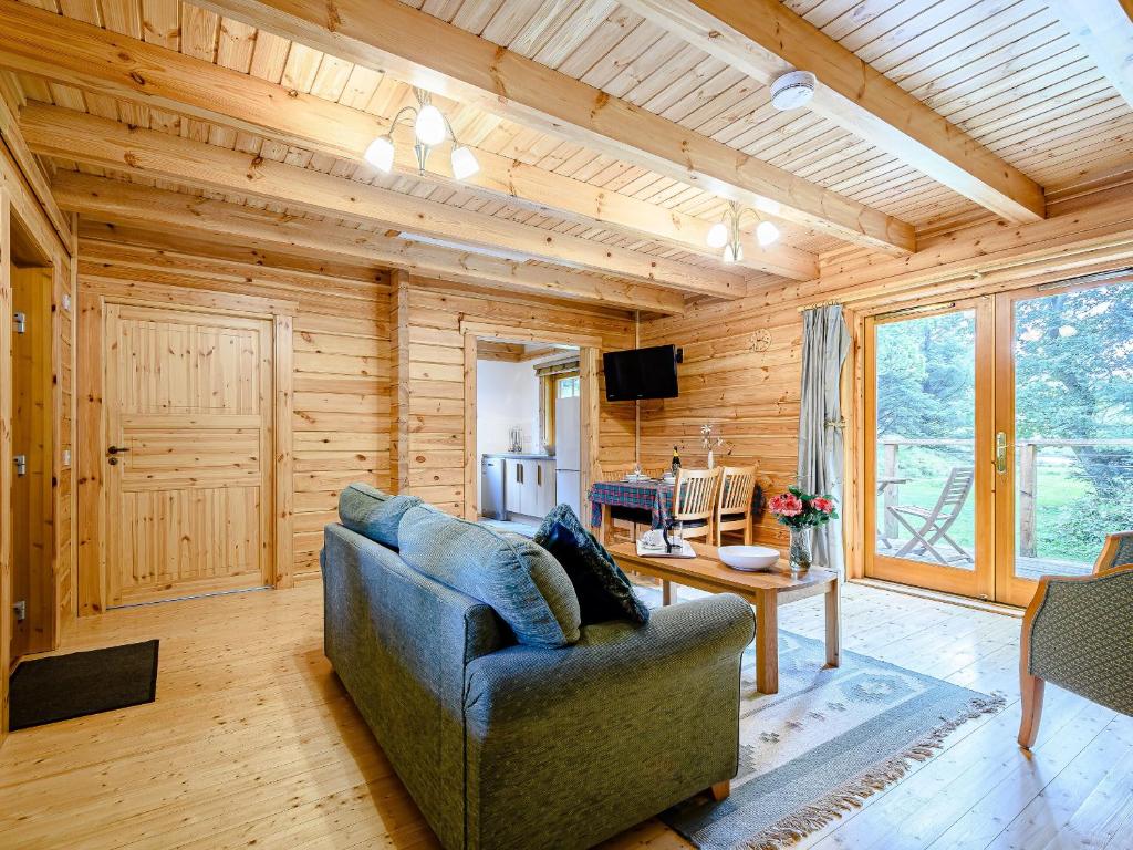 a living room with a blue couch in a wooden house at Larch - Uk31134 in Killin