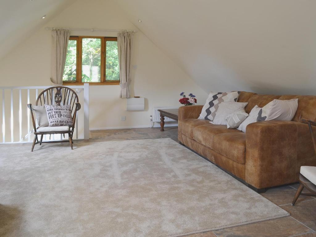 a living room with a brown couch and a chair at Forest Cottage in Northwold