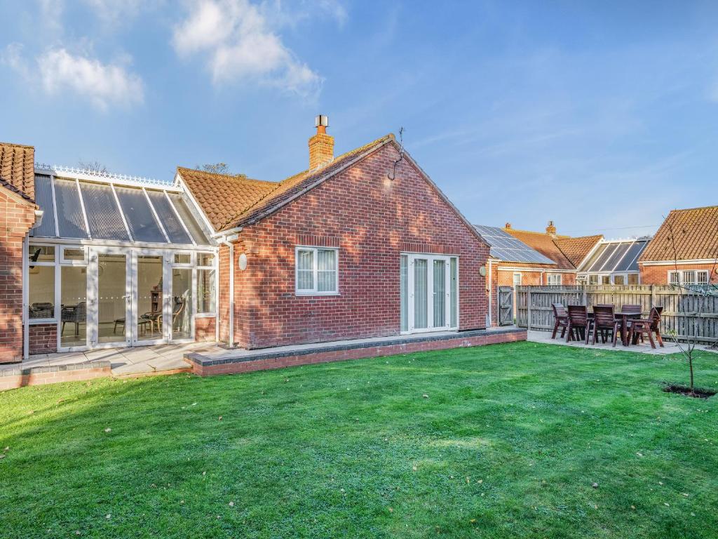 a yard with a brick house with a large lawn at The Beeches in Sea Palling