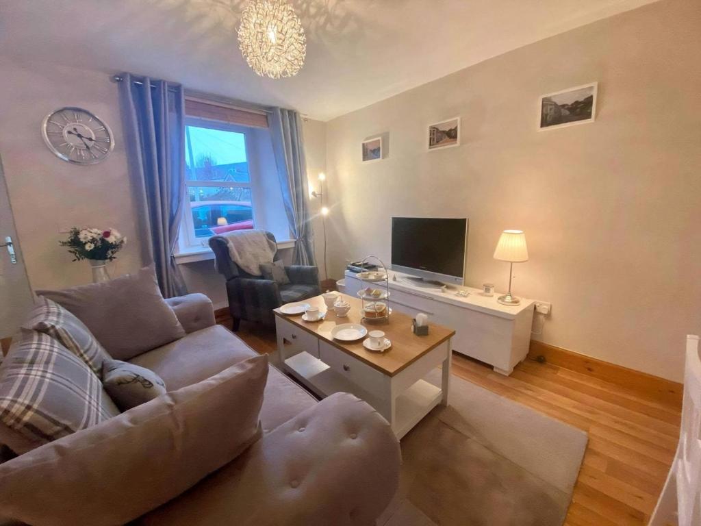 a living room with a couch and a tv at Heather Cottage in Lauder