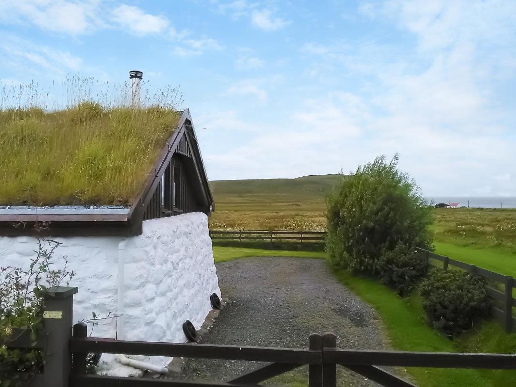 a building with a grass roof with a fence at Tawmans in Kilmuir