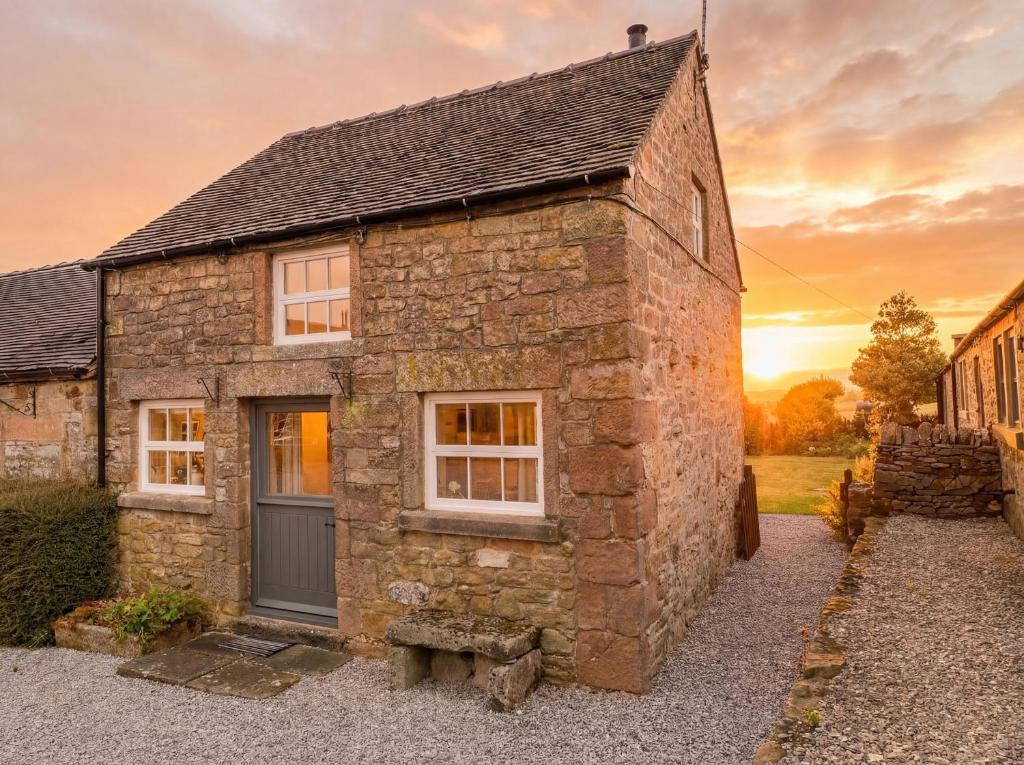 an old stone house with a sunset in the background at The Dairy in Bakewell
