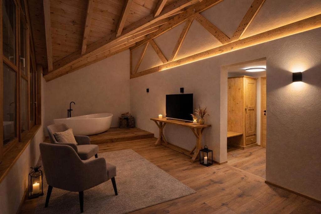 a living room with a tub and a television and a couch at Kapitel 7 Boutique-Hotel in Raron